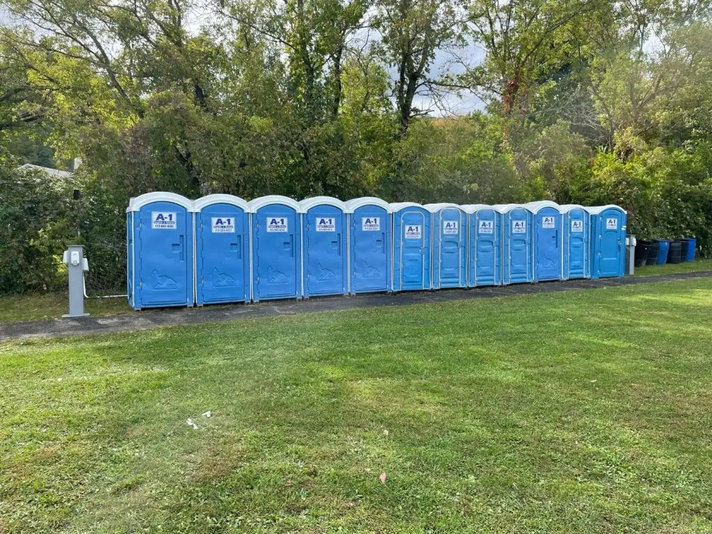 Long line of A1 portable toilets set up on a grass field for an event
