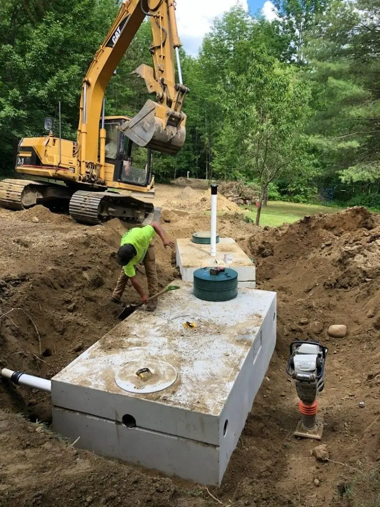 Excavator setting a new concrete septic tank