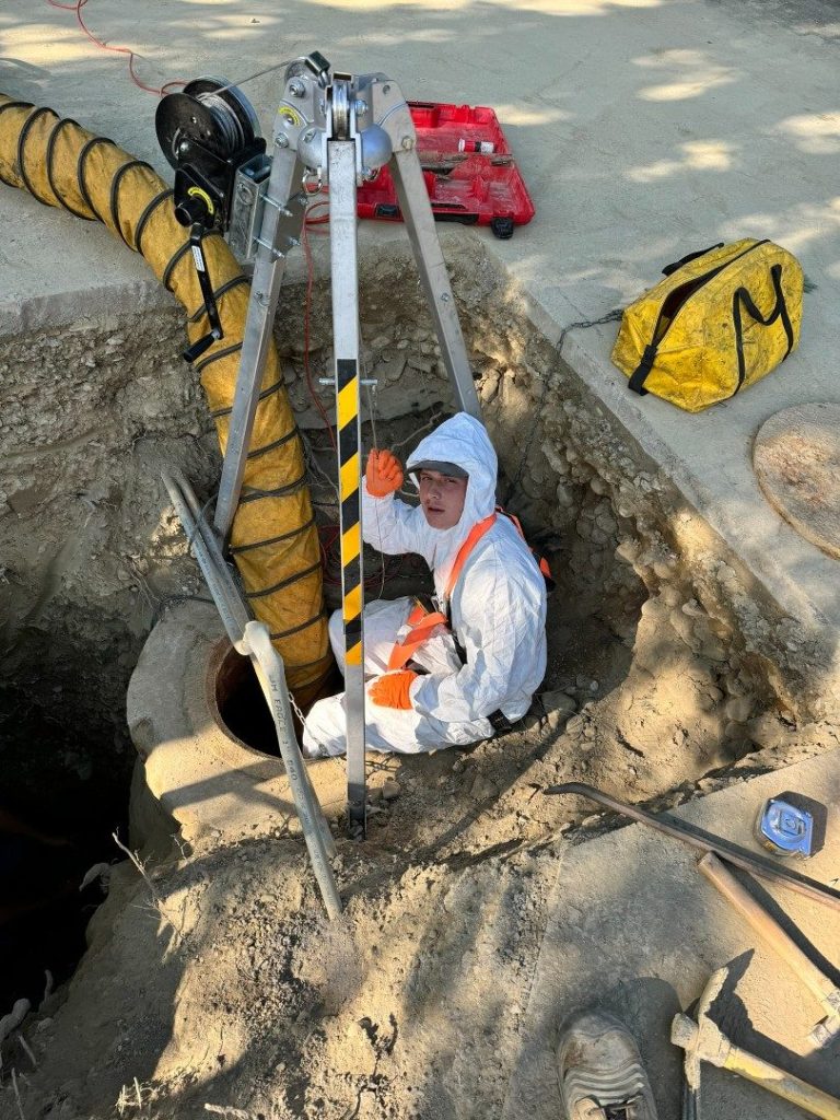 A1 technician in protective gear working inside a sewer manhole